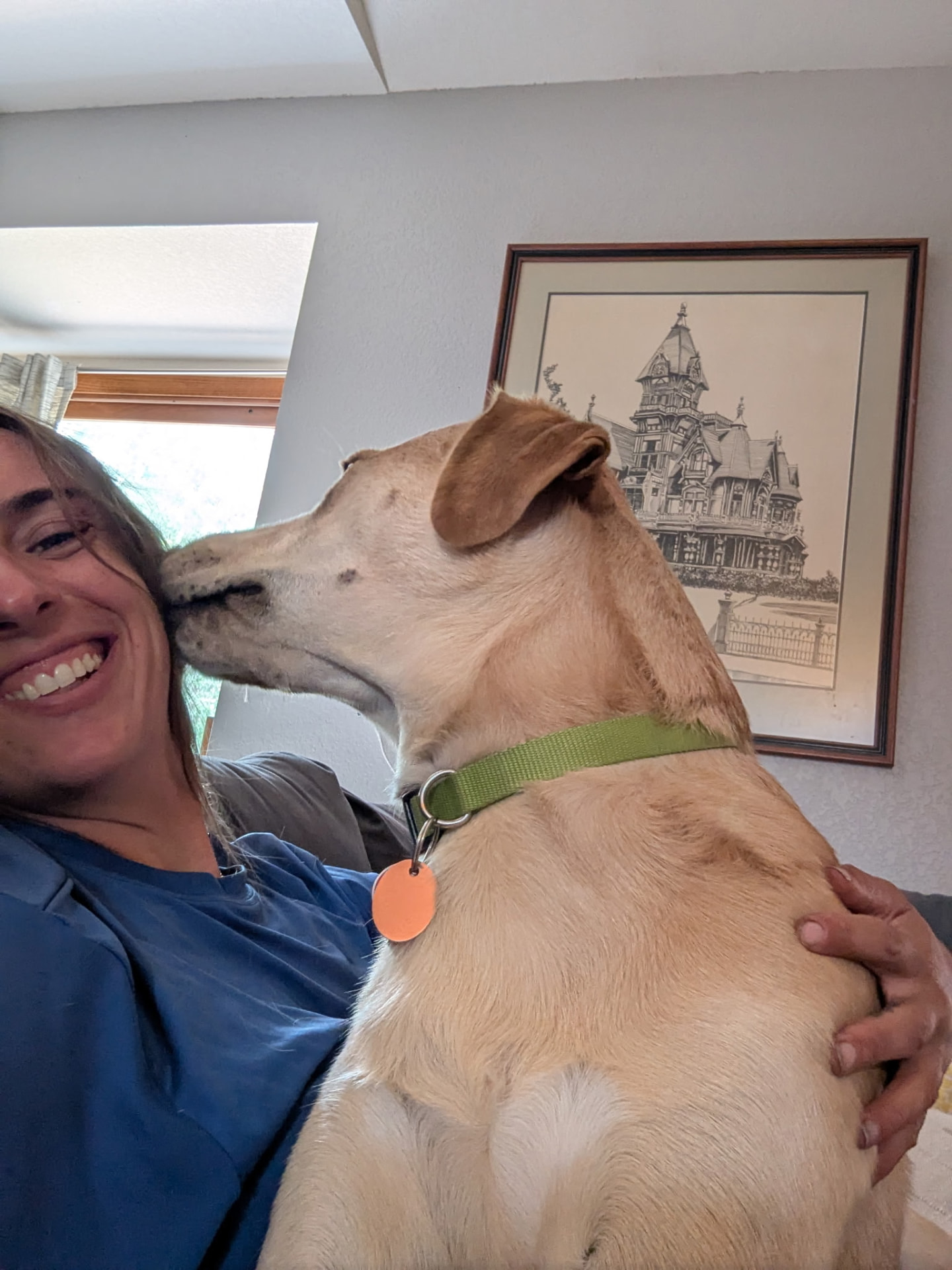 Sarah getting a kiss from a happy yellow dog during a Fort Collins pet sitting visit