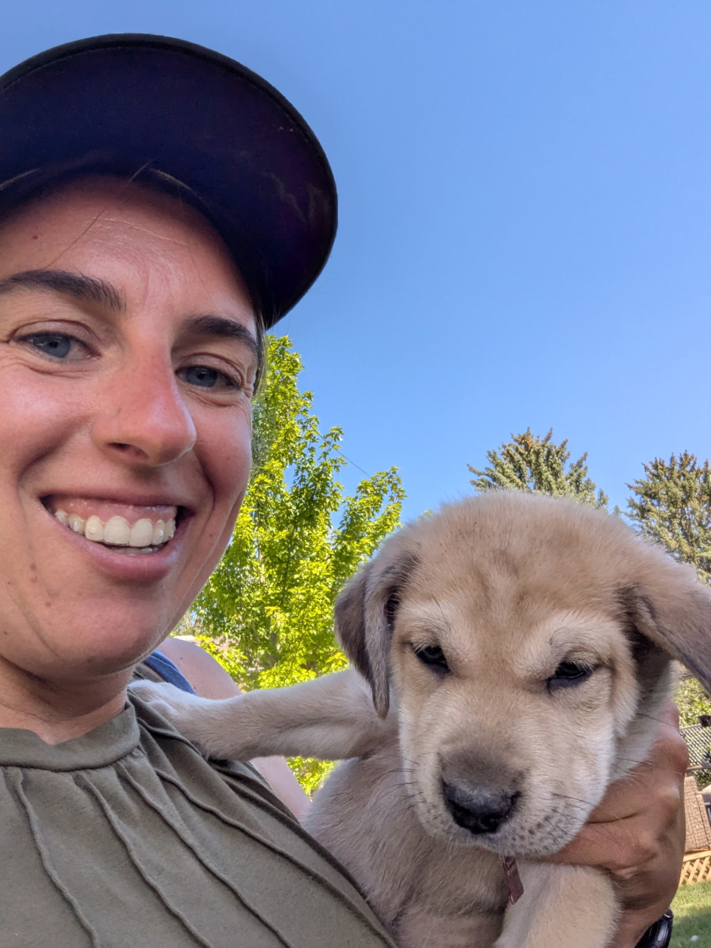 Sarah smiling with a fluffy puppy in her arms in Loveland, Colorado